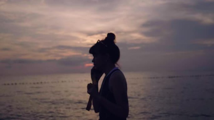 日落时分，年轻女子在海上用智能手机打字