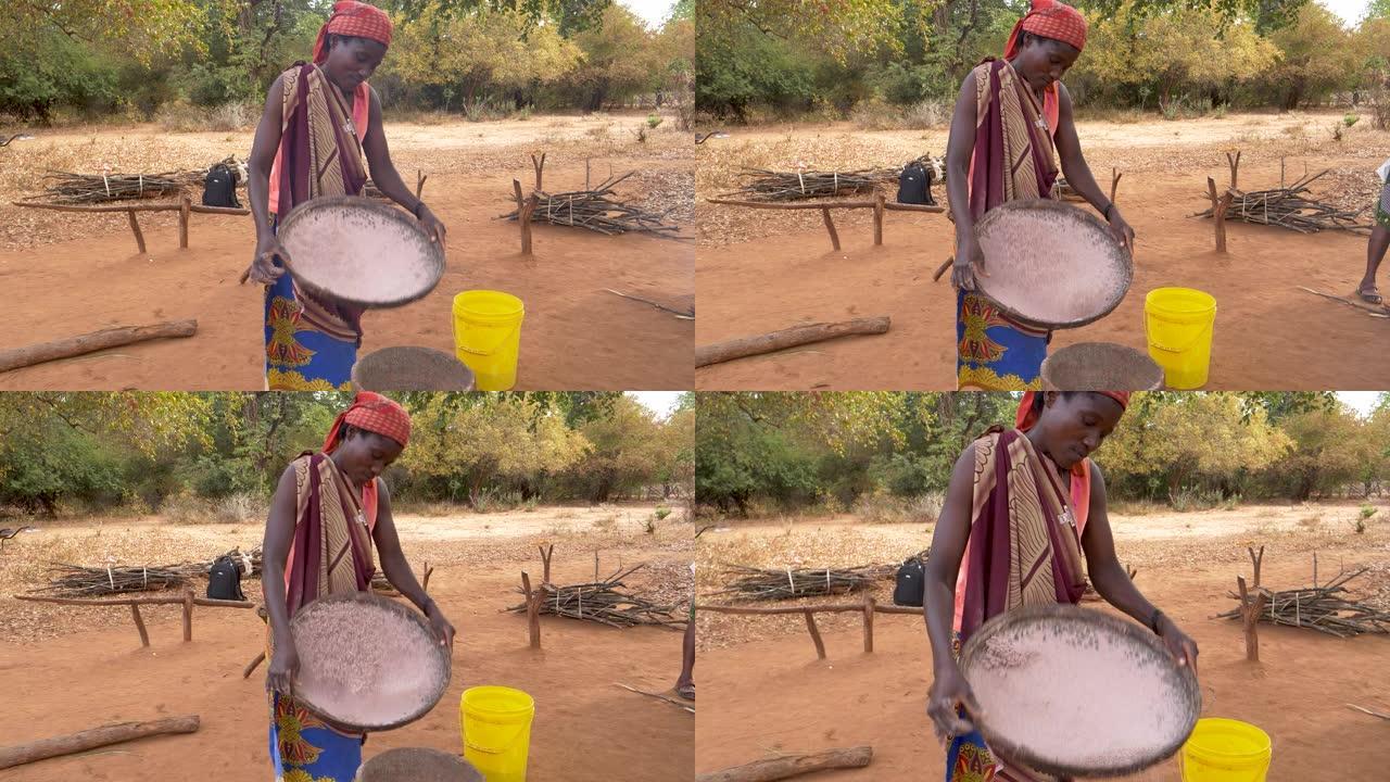 一名妇女用一种古老的传统方法筛选高粱，津巴布韦