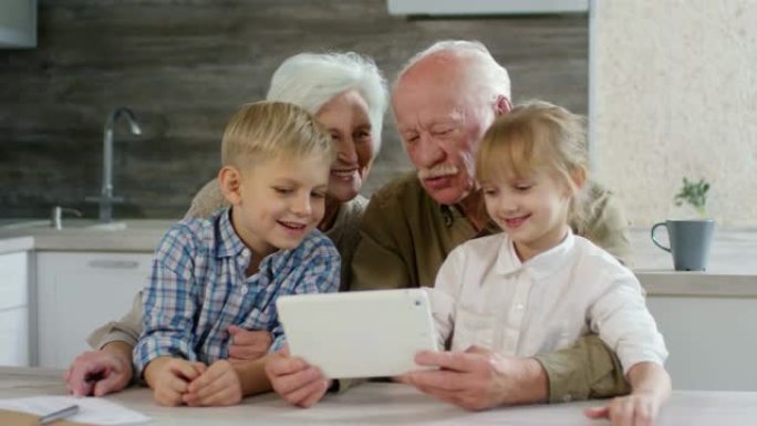 祖父母与孩子们一起使用平板电脑观看动画片
