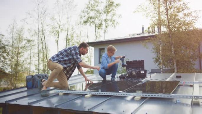 父子俩用钻头将太阳能电池板安装到金属基础上。他们在晴天和高五时在房屋屋顶上工作。家庭生态可再生能源的
