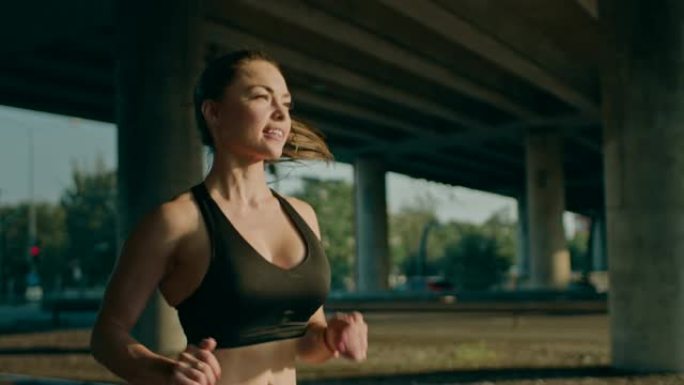 慢动作特写镜头，一个穿着黑色运动上衣的美丽丰满的健身女孩在阳光明媚的街道上慢跑。她在城市环境中奔跑，
