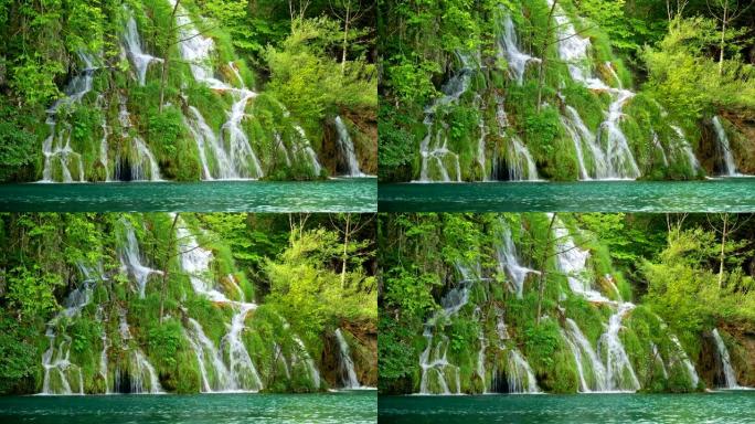 可爱的瀑布，有许多小瀑布，周围是丰富的绿色植物，流入克罗地亚十六湖国家公园的绿松石色湖泊。4K