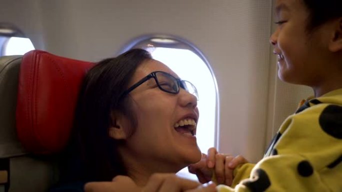快乐的亚洲母亲和儿子在飞机上。
