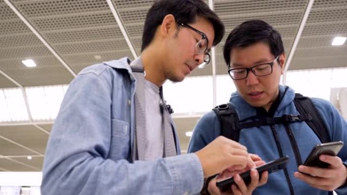 亚洲男子在机场寻找他们的航班时刻表