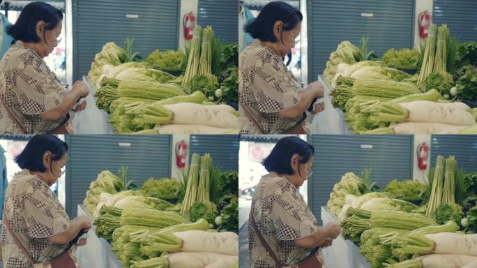 购买水果和蔬菜的亚洲高级妇女站在农贸市场
