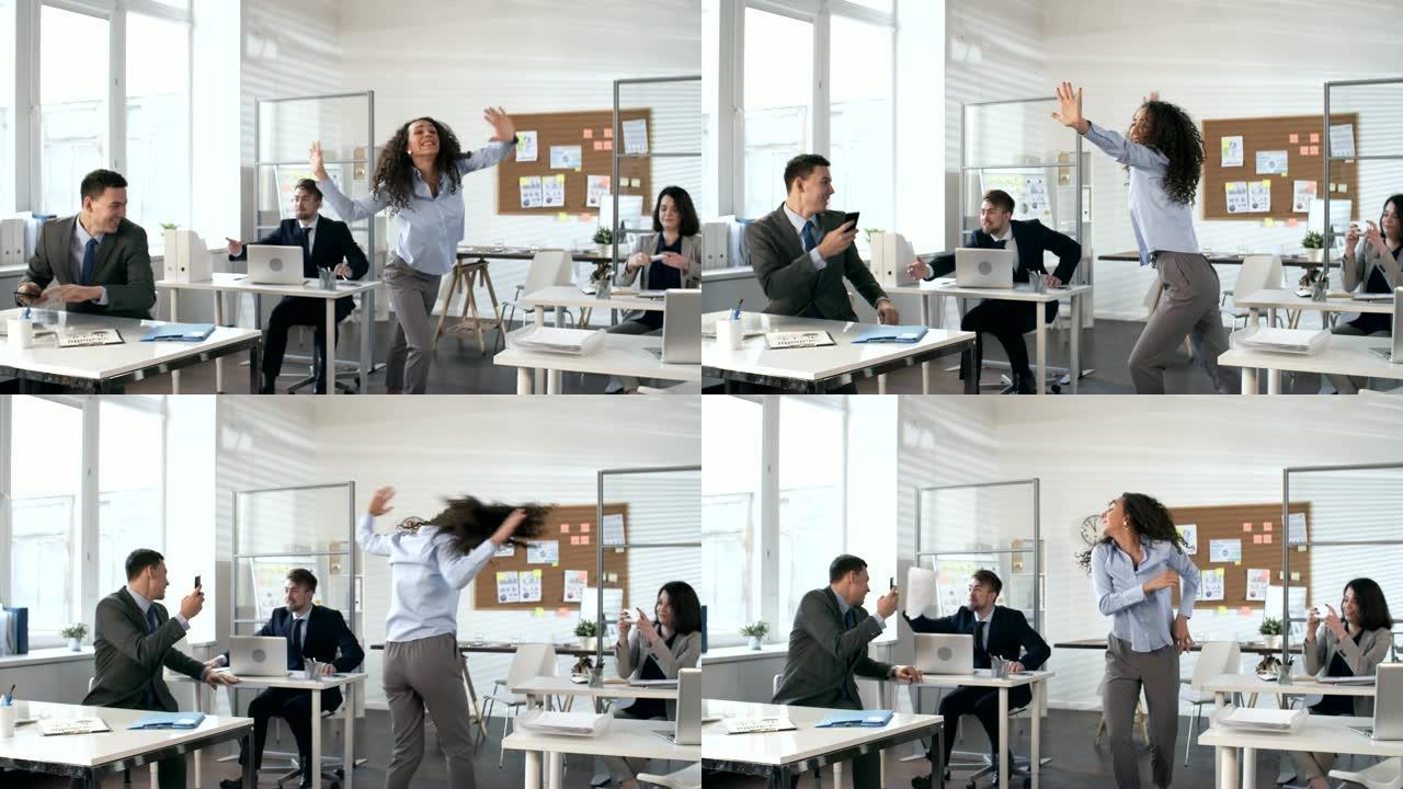 无忧无虑的女人在办公室的业务团队面前跳舞
