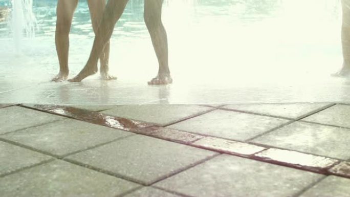 在水上公园游泳池喷泉玩耍的孩子们的腿