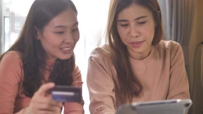 两名亚洲妇女在家中使用数字平板电脑在线购物