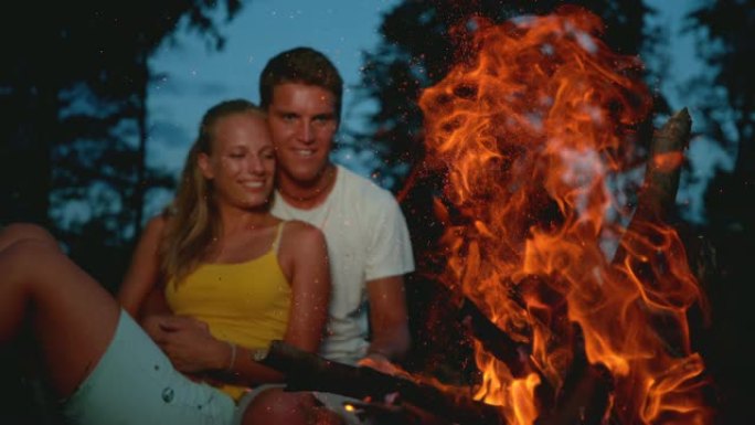 特写: 微笑的年轻夫妇在篝火旁享受一个平静的夏日夜晚。