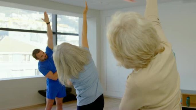教练协助高级女性表演瑜伽4k