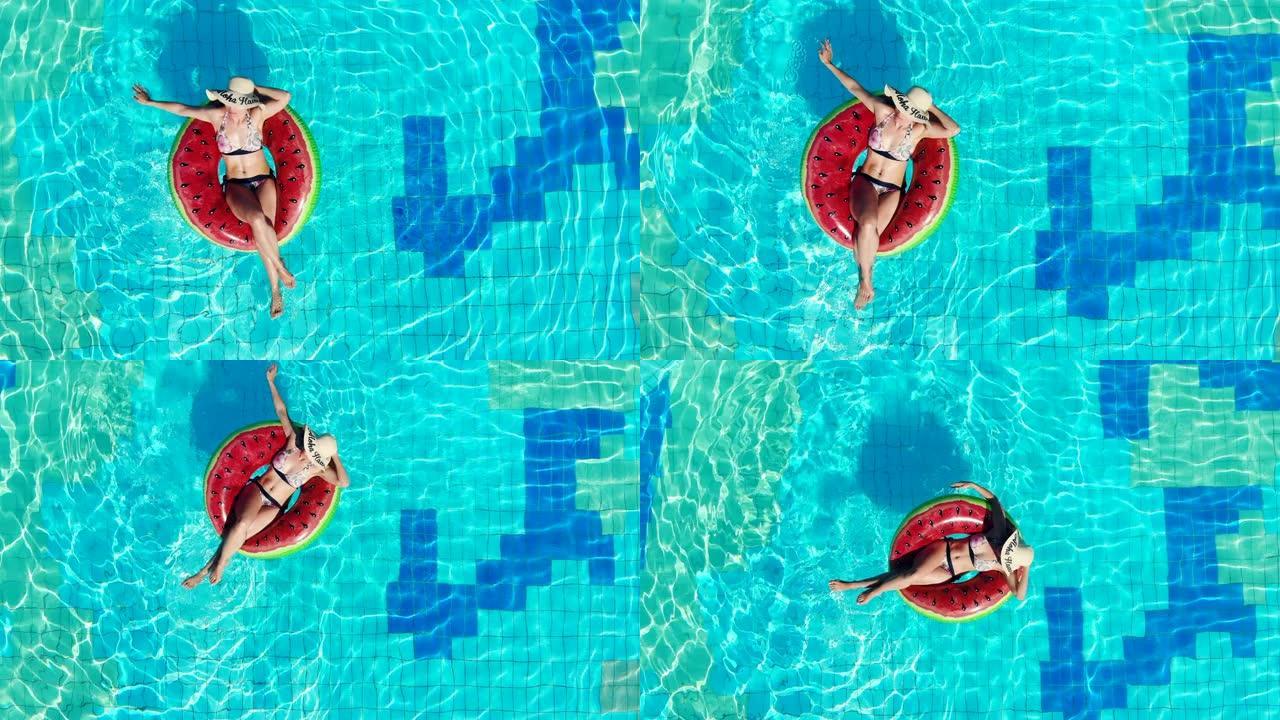 穿着泳衣的休息妇女漂浮在游泳池的橡胶圈上。