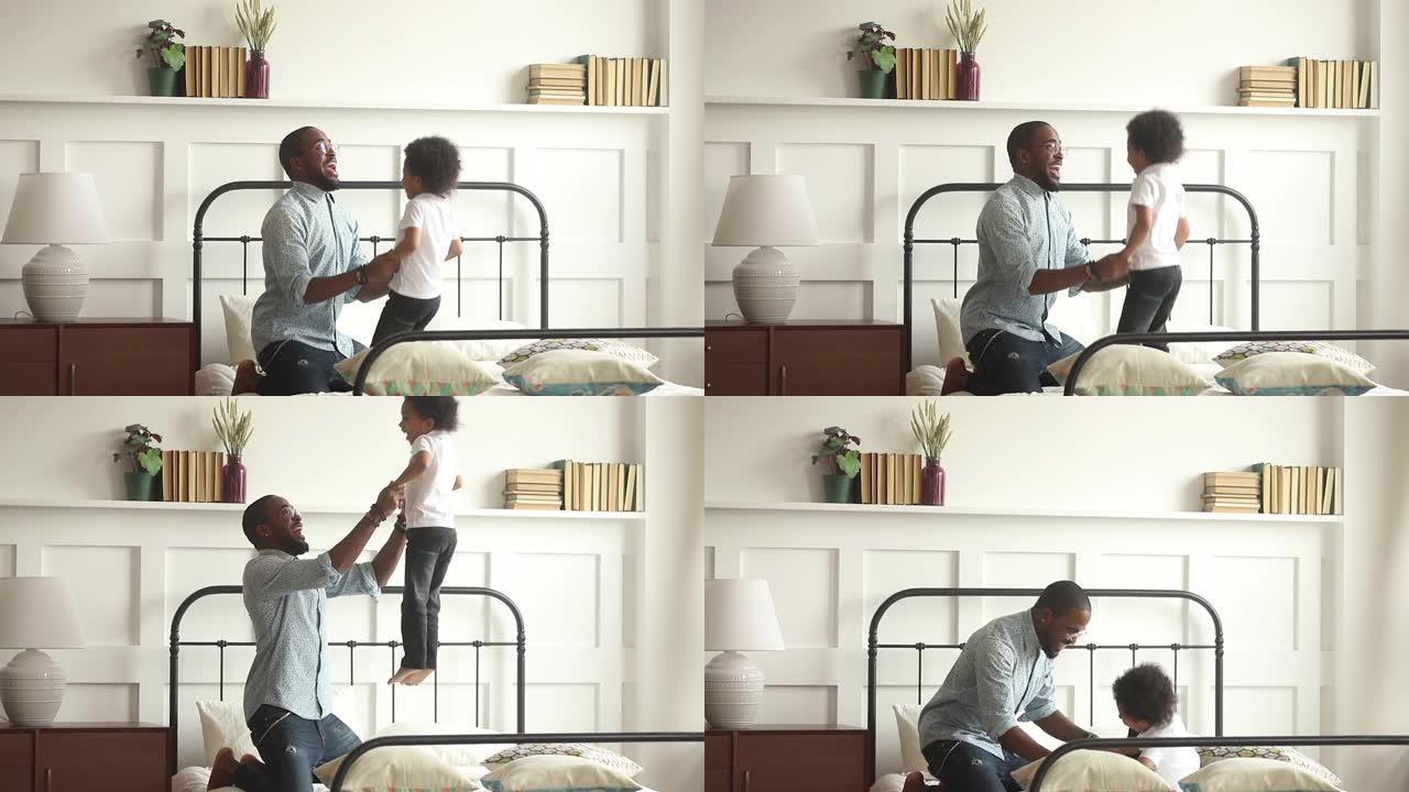 快乐的非洲父亲玩小孩儿子在床上跳