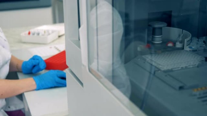 当实验室工作人员在电脑前工作时，带血的管子在离心机里被检查。