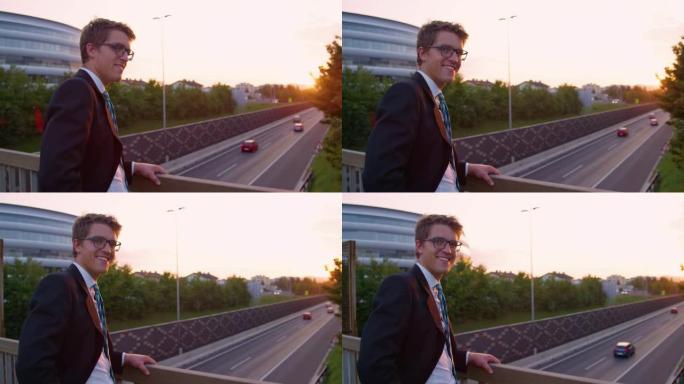 肖像: 成功的雅皮士在高速公路上方观看日落时转身