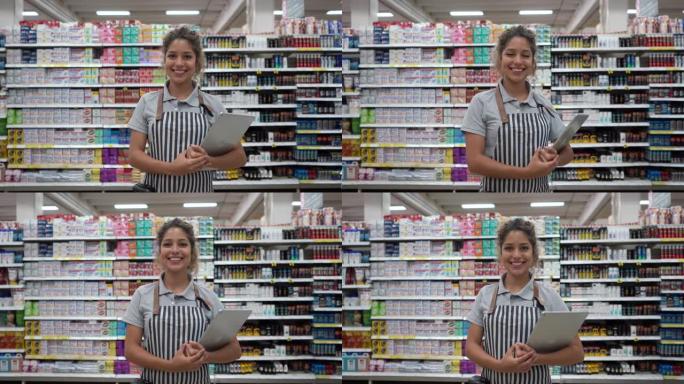在超市工作的拉丁美洲妇女拿着平板电脑送货，面对相机微笑