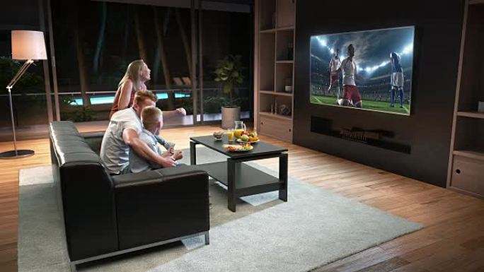 一家人正在电视上观看足球时刻并庆祝进球