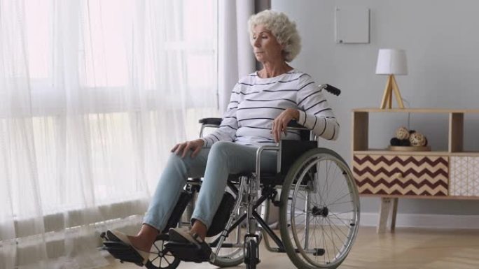 体贴悲伤的老妇人独自坐在轮椅上在家