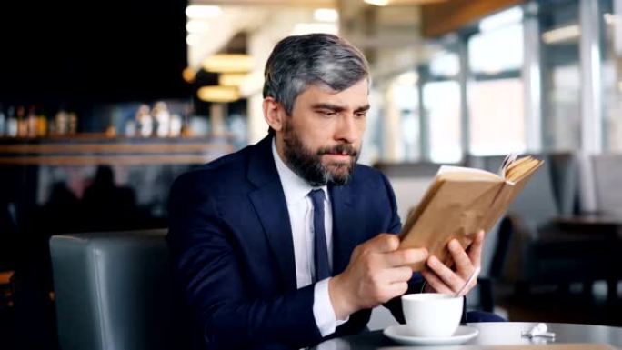 聪明的企业家独自坐在咖啡馆里看书，享受有趣的故事