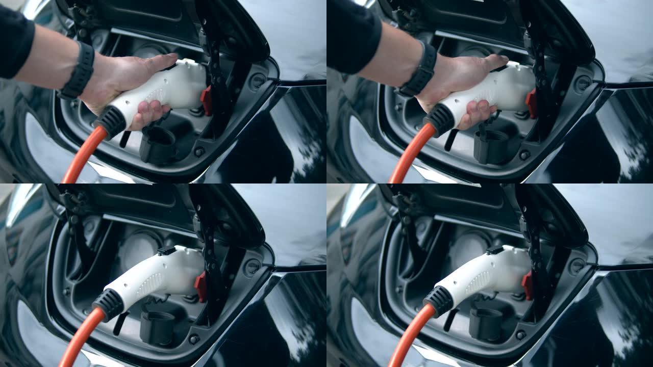 一名男子将充电电缆插入他的电动汽车。创新的电动混合动力汽车充电。