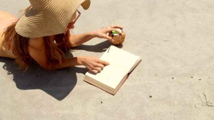 戴帽子的白人妇女在海滩上看书的高角度视角4k