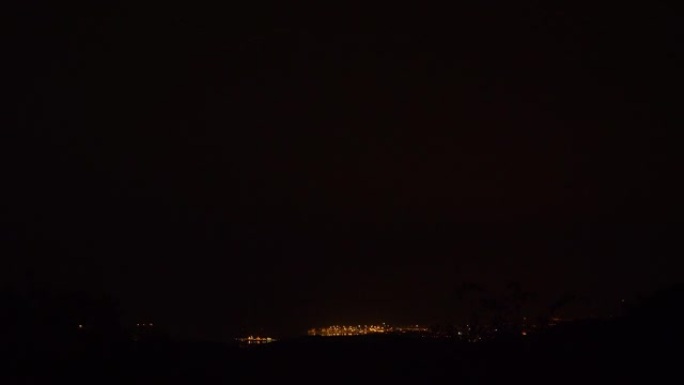 夜间照明螺栓撞击远处城市的壮观镜头。