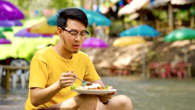 亚洲男子放松饮食垫Kra Pao，最受欢迎的泰国菜之一，罗勒辣猪肉米饭