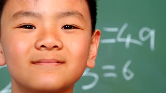 4k学校教室里，亚洲男生站在黑板上的特写镜头