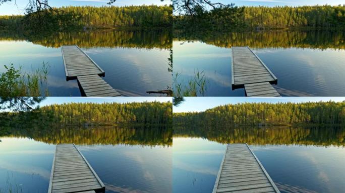 芬兰的自然。湖上的码头。背景中的松树林映衬着美丽的蓝色湖水。摄像机向前移动。Steadicam镜头，