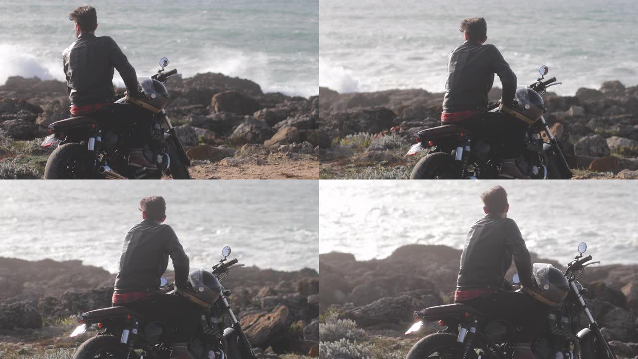 背景式男子坐在经典摩托车上凝视海滨