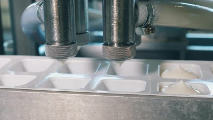 自动化机器将乳制品倒入工厂的容器中。