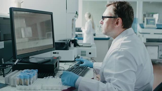 男科学家坐在实验室的工作场所，使用个人计算机。屏幕显示DNA分析。我拥有创新设备的背景遗传学研究中心