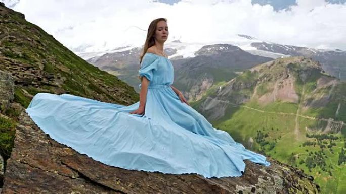 穿着优雅礼服的女人坐在岩石上。山地景观