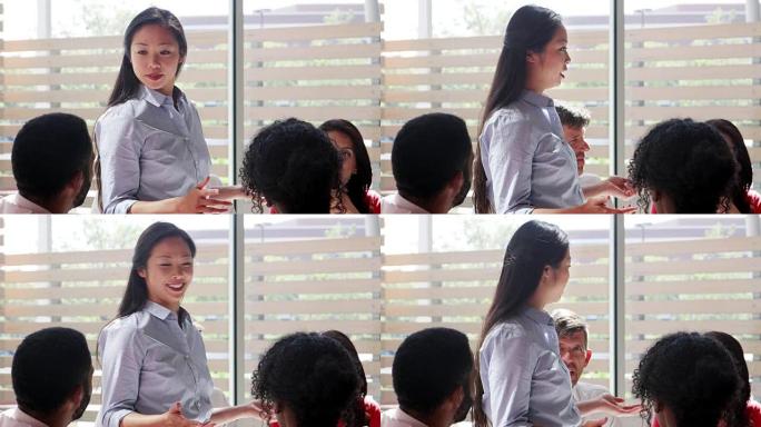 一位年轻的亚洲女商人在办公室的会议上讲话