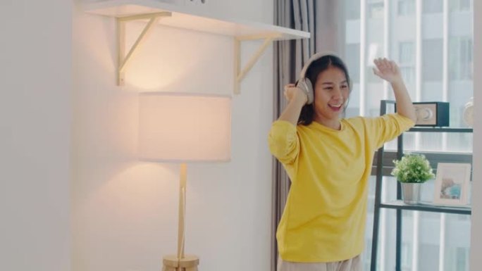 快乐美丽的亚洲女人在家庭房间里欢快跳舞，在日冕病毒流行期间在家休闲活动