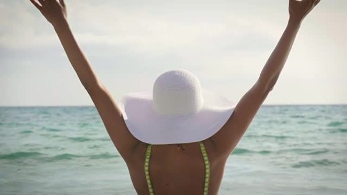一个美丽的年轻女孩的肖像，女人在海上晒日光浴，穿着泳衣，白帽子，海空背景。