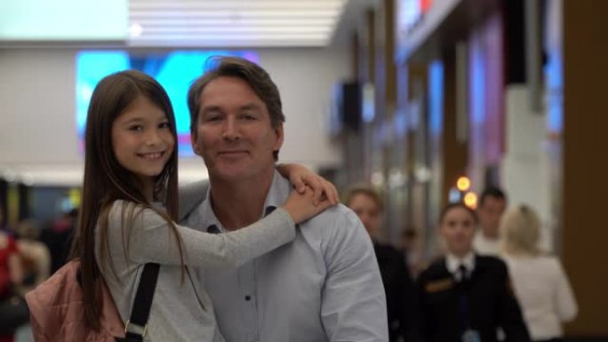 慈爱的父亲带着女儿在机场看着相机微笑