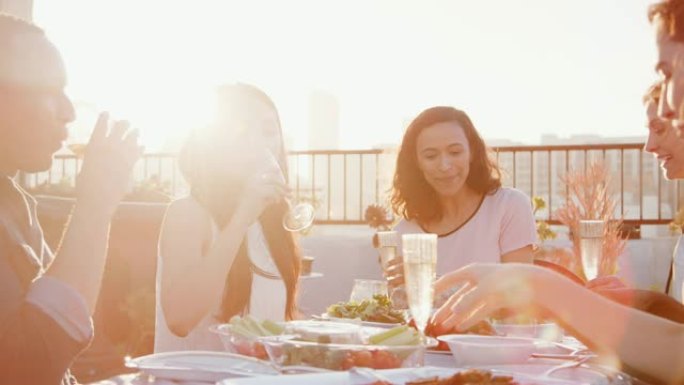 朋友聚集在屋顶露台上用餐，背景为城市天际线