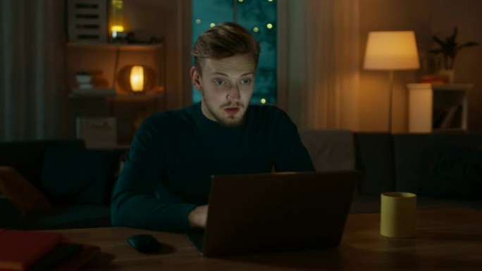 英俊的微笑男人坐在家里的办公桌前在笔记本电脑上工作，他进行视频通话并与朋友交谈。晚上舒适的客厅。