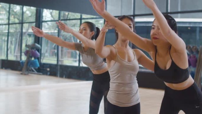 年轻的亚洲运动型有魅力的人与教练一起练习瑜伽课。亚洲妇女团体在健身工作室锻炼健康的生活方式。体育活动