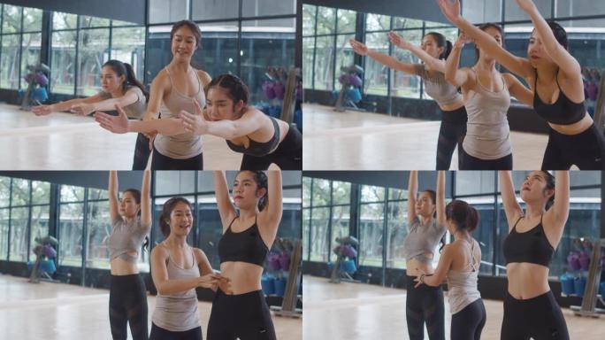 年轻的亚洲运动型有魅力的人与教练一起练习瑜伽课。亚洲妇女团体在健身工作室锻炼健康的生活方式。体育活动