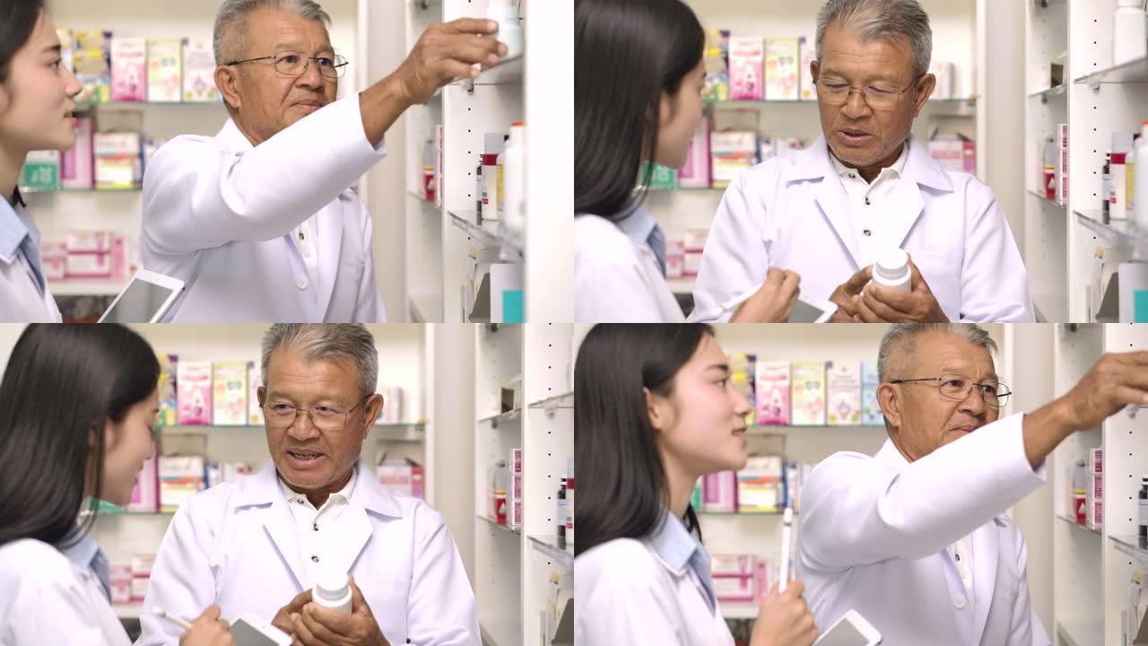 两名亚洲药剂师在药房检查药品。资深男药师和他年轻的女同事站在货架前拿药，在药店用触摸板电脑互相咨询。
