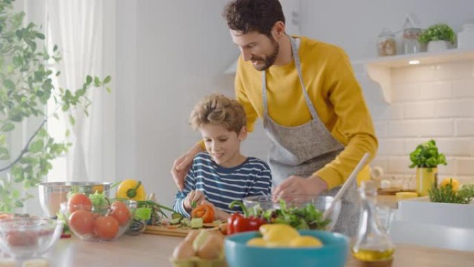 在厨房: 父亲和可爱的小儿子一起烹饪健康的晚餐。爸爸教小男孩健康的习惯，以及如何切蔬菜做沙拉。快乐的
