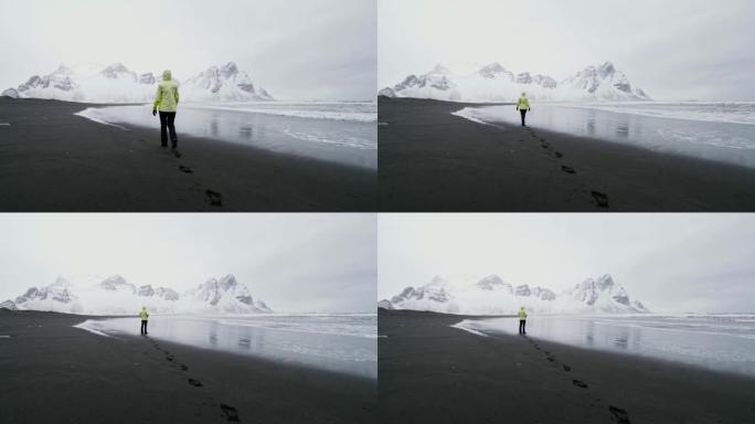 WS妇女在冰岛斯托克尼斯海滩的黑沙滩上行走