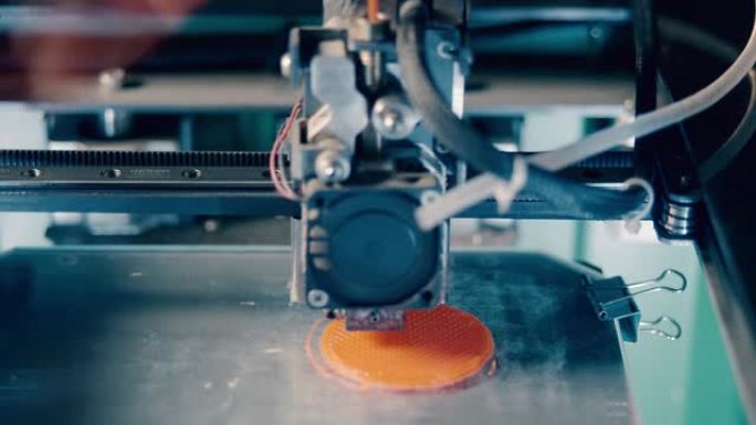 圆形橙色盘子正在3D打印。三维3d打印机在3d打印实验室工作。