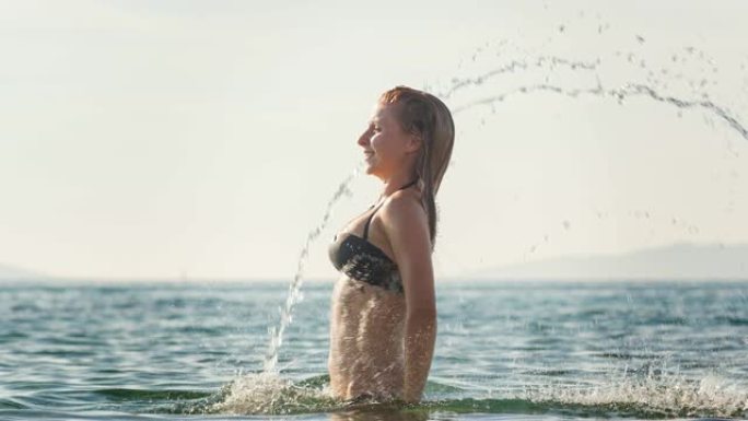 女人站在海洋中，向后翻转湿头发