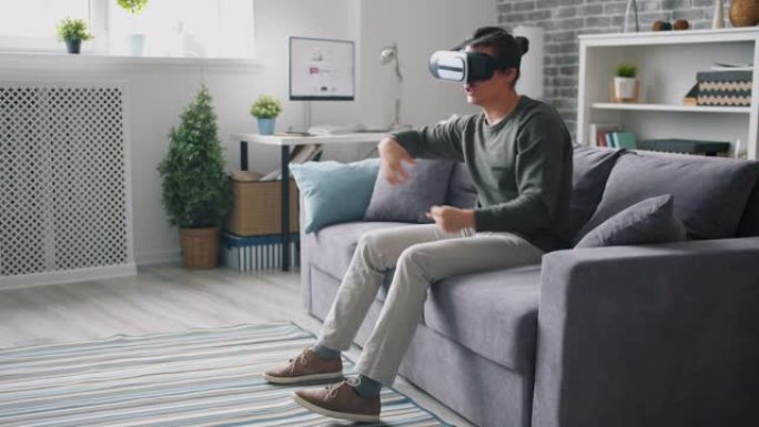 快乐的人在家里戴着虚拟现实眼镜坐在沙发上移动手臂