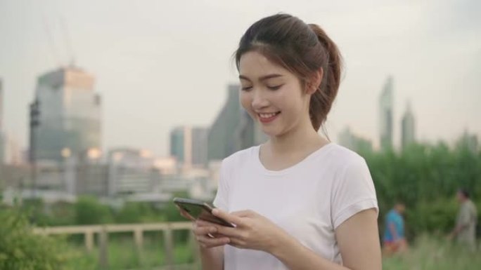 慢动作-开朗的亚洲旅游博主女人使用智能手机的方向，并在城市的街道上旅行时在位置地图上寻找。生活方式背