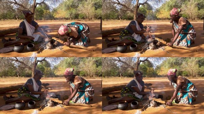 津巴布韦，两名妇女在传统的陶罐中煮高粱