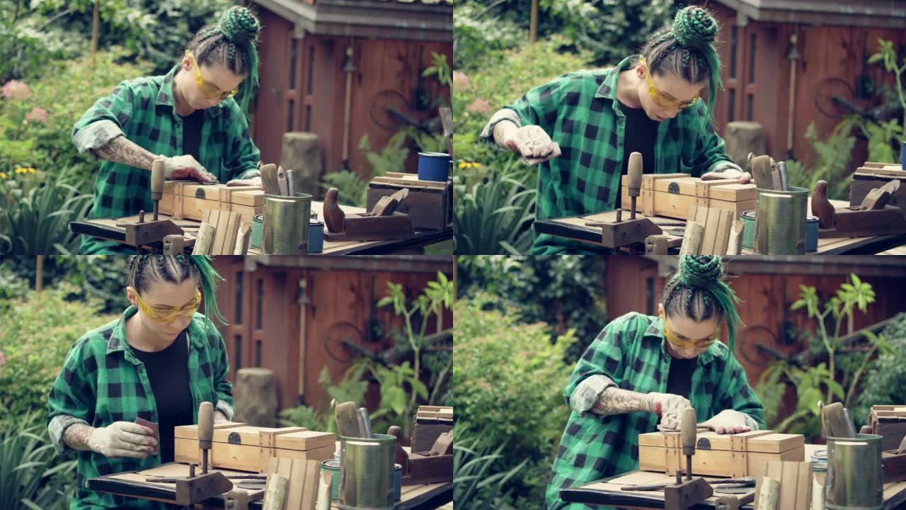 花园DIY。纹身女人抛光木制家具。