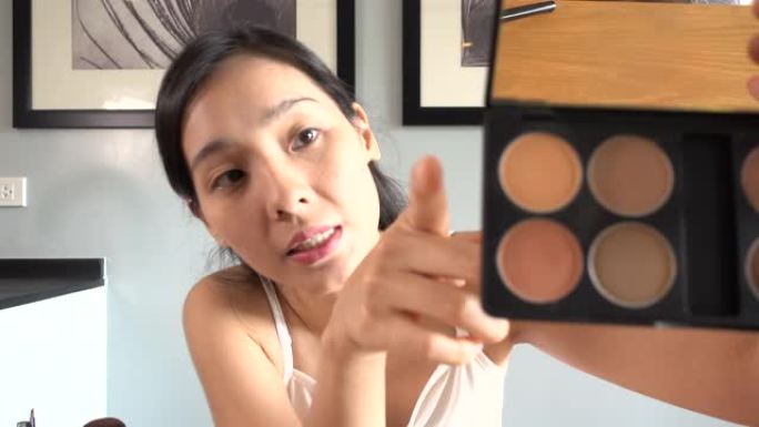 年轻的亚洲女性在她的视频博客上制作化妆教程